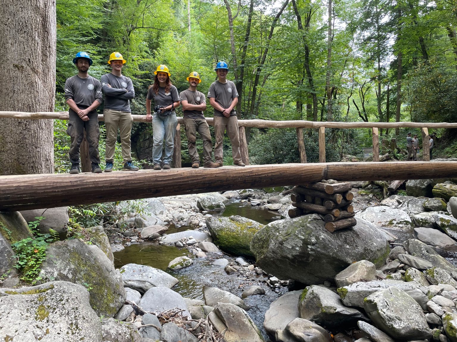 Members of the National Park Service Trails Forever crew, which is funded by Friends of the Smokies, stand on a footlog they installed during the intensive rehabilitation of Ramsey Cascades Trail they completed between 2022 and 2024 with support from American Conservation Experience, Southeast Conservation Corps, and volunteers. Photo courtesy of National Park Service.