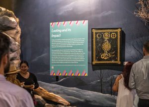 A painting by Atsei Cooper (Eastern Band of Cherokee Indians) with accompanying wall text from Disruption, an exhibition currently on view at the Museum of the Cherokee Indian. Image courtesy of the Museum of the Cherokee Indian.
