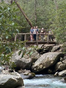 Retired biology teacher Pat DeRoos, who attended the 2022 Great Smokies Eco-Adventure, crosses a footbridge with her daughter Kimberly and granddaughters Tinsley and Torrey. DeRoos’ granddaughters were especially excited to learn that a species previously undocumented in the park had been discovered on their trip. Photo by Barb Witt. 