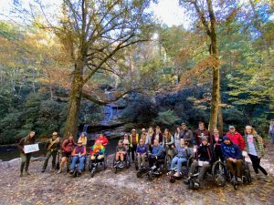 Participants in a fall 2023 hike to Tom Branch Falls in the park’s Deep Creek area gather for a group photo. In 2023, a total of 220 people, of whom 44 used adaptive technologies, participated in the adaptive program. Photo provided by Catalyst Sports.