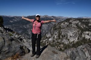 A panoramic view spreads out behind Jacki Harp during a hike in Yosemite National Park, one of the many wild places she’s explored during her cross-country career with REI. Photo provided by Jacki Harp. 