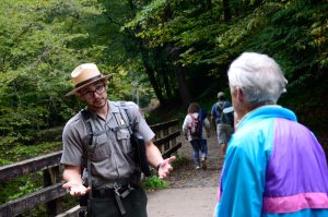 Seasonal Interpretive Ranger Cody Boettner answers questions during a guided hike on Deep Creek Trail this fall. Photo by Holly Kays, courtesy of Smokies Life. 