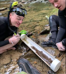 Jonathan Cox (left), wetlands biology technician for the park, looks in astonishment at an eastern hellbender captured while monitoring populations in Pisgah National Forest. Photo by Ben Dalton, provided by NC Wildlife Resources Commission. 