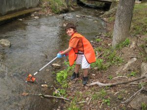 A young volunteer picks a chip bag out of a stream, keeping the natural environment and the plants and animals living there safe from litter. Photo courtesy of National Park Service. 