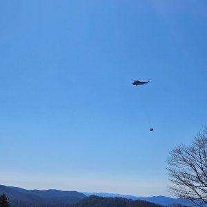A helicopter flies a load of supplies to LeConte Lodge March 19 before delivering 80 locust logs to the Appalachian Trail later that afternoon. Photo by Franklin LaFond.