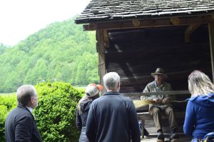 The Branch Out group watches Volunteer-In-Park Bill Douglas demonstrate traditional broom-making at the Mountain Farm Museum. Photo by Holly Kays, courtesy of Smokies Life.