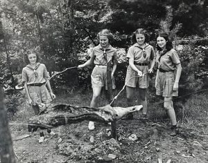 Elizabeth Hayes (from left), Dot Hill, Edythe Mae Kincaid, and Ann Rita Walland roast their dinner meal during a camp session in the 1930s. Photo courtesy of Girl Scout Museum at Daisy’s Place.