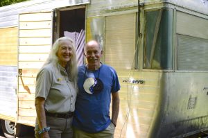 Two people, one in a ranger uniform, stand together outside of an RV.