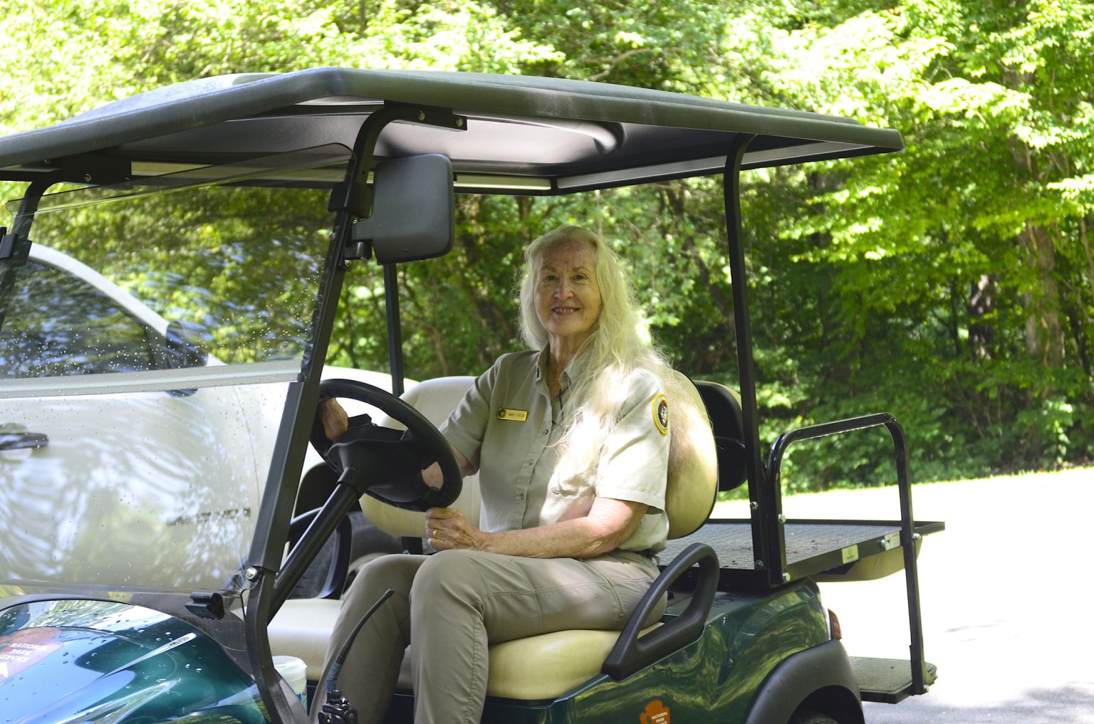 Smiling woman in a ranger uniform sitting in a golf cart