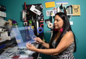 A woman looks through art supplies and prints on a desk.