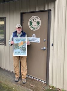 A man in a baseball cap stands in front of a doorway holding a WPA poster.