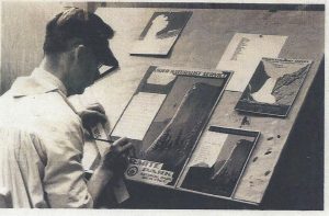 A black and white photo of an artist creating posters