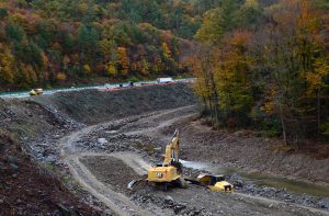 A construction crane sits in the middle of a muddy riverbed