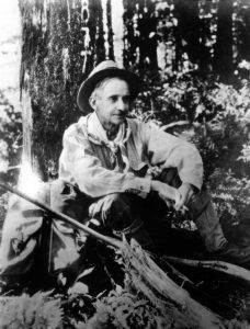 A man in a hat sitting in the woods