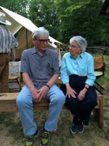 A man and woman sit talking on a bench