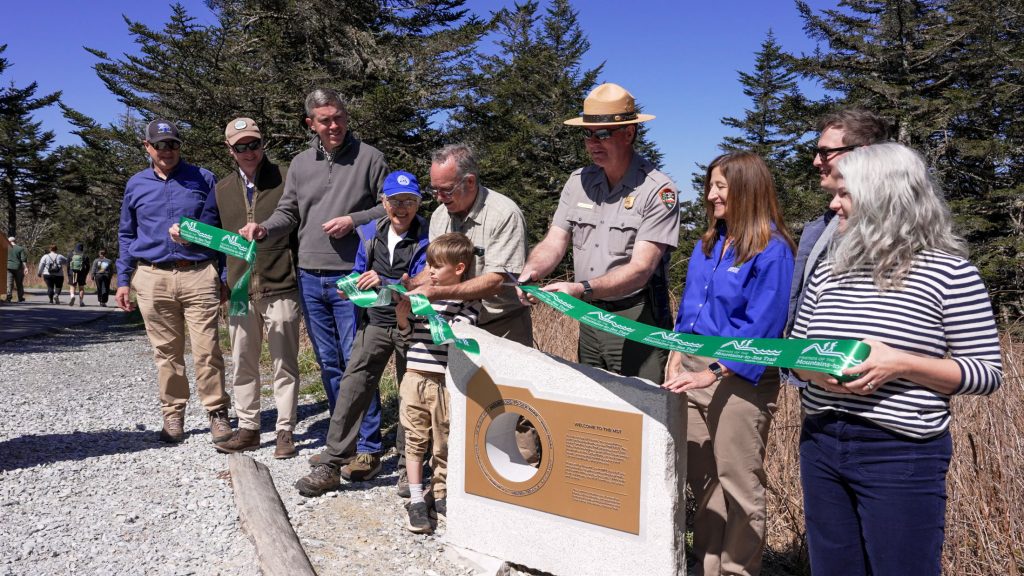 A group of people holding a green ribbon for a ceremony