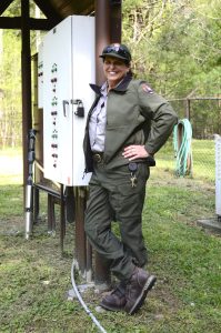 A woman in a park ranger uniform standing next to a utility box