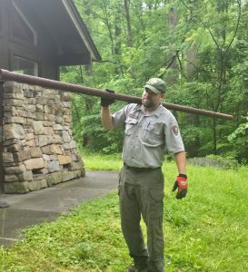 A park ranger carrying a pipe over his shoulder